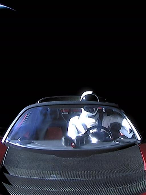 Zusehen ist im Hintergrund der Mond und im Vordergrund eine Auto mit einem Astronauten am Steuer