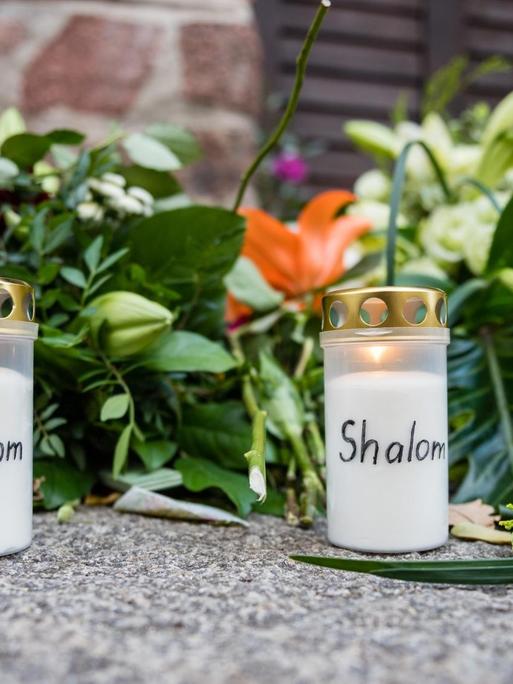 Blumen und Kerzen mit der Aufschrift Shalom vor der Synagoge in Halle.
