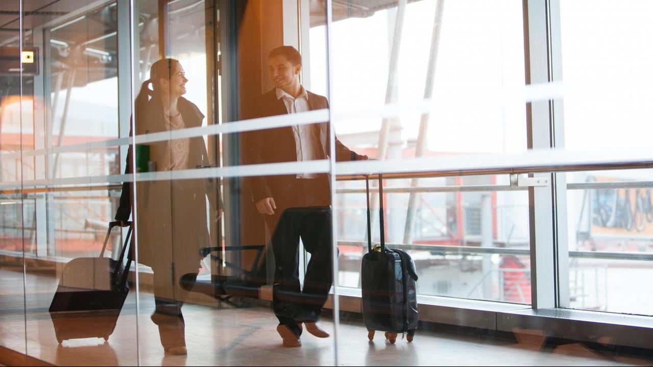 Ein Mann und eine Frau laufen am Flughafen Hamburg zu ihrem Gate (Illustration, Symbolbild)