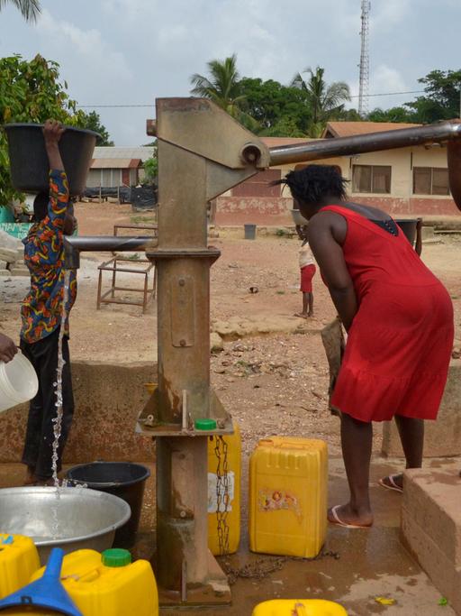 Frauen pumpen Wasser im ghanaischen Dorf Bonsaado