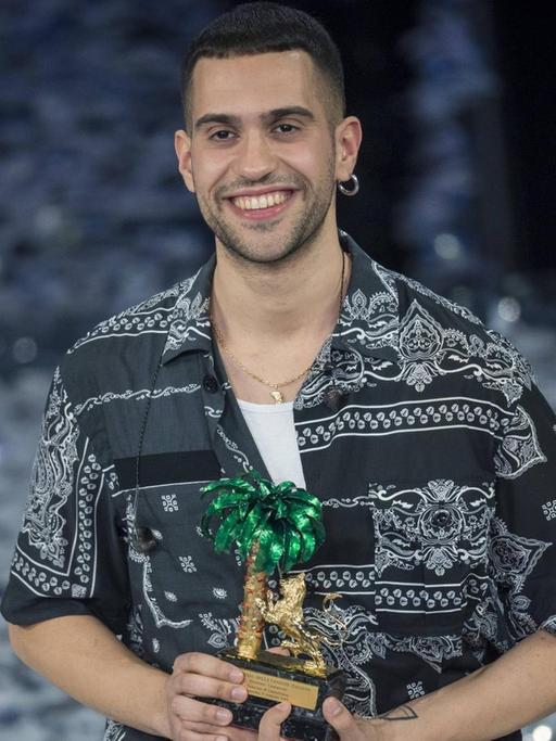 Der italienische Sänger Mahmood hat das Schlagerfestival Sanremo gewonnen. Ein lächelnder junger Mann mit einer Trophäe auf einer Bühne.