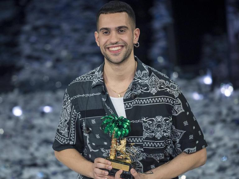 Der italienische Sänger Mahmood hat das Schlagerfestival Sanremo gewonnen. Ein lächelnder junger Mann mit einer Trophäe auf einer Bühne.