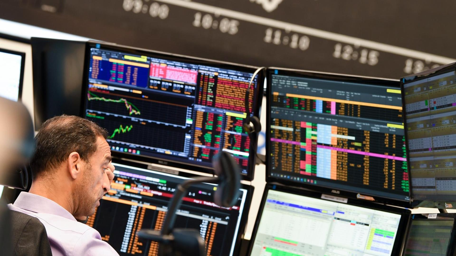 Ein Aktienhändler beobachtet auf dem Parkett der Frankfurter Wertpapierbörse vor der Tafel mit der fallenden Dax-Kurve seine Monitore. Die sich verschärfende Corona-Krise mit schnell steigenden Infektionszahlen und einem drohenden «Lockdown» des öffentlichen Lebens in Deutschland haben den deutschen Aktienmarkt stark belastet.