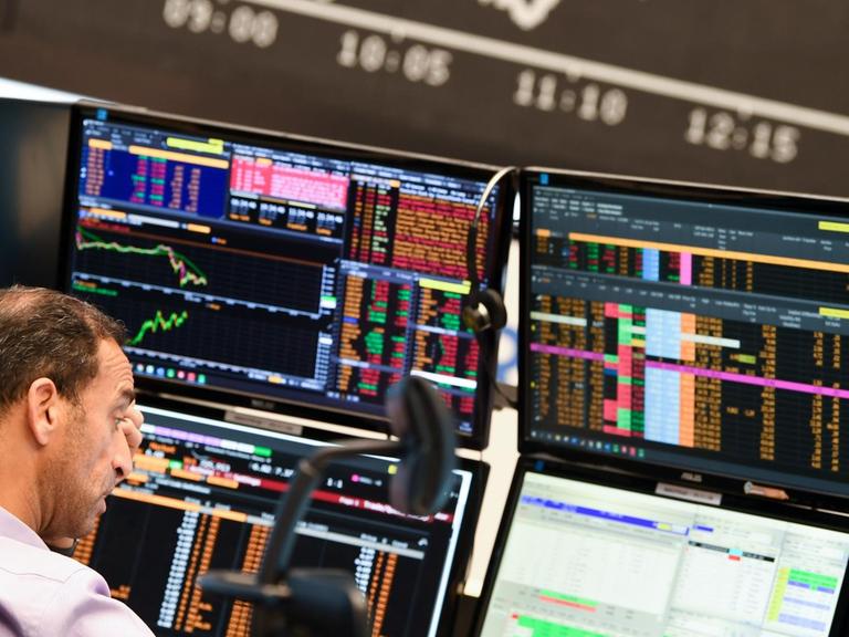 Ein Aktienhändler beobachtet auf dem Parkett der Frankfurter Wertpapierbörse vor der Tafel mit der fallenden Dax-Kurve seine Monitore. Die sich verschärfende Corona-Krise mit schnell steigenden Infektionszahlen und einem drohenden «Lockdown» des öffentlichen Lebens in Deutschland haben den deutschen Aktienmarkt stark belastet.