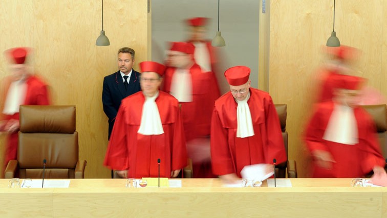 Die Richter kommen in den Raum und nehmen ihre Plätze ein.