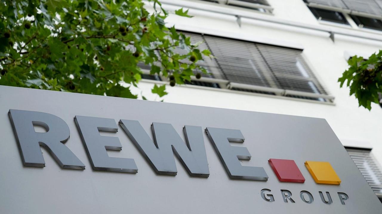 Hauptsitz der REWE Group in Köln, ein Schild mit dem Konzernnamen steht vor einem Gebäude. Hauptsitz der REWE Group in Köln, ein Schild mit dem Konzernnamen steht vor einem Gebäude.