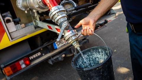 Einsatzkräfte der Freiwilligen Feuerwehr Lauenau zapfen Löschwasser aus dem Tank eines ihrer Einsatzfahrzeuge. In der Gemeinde im Landkreis Schaumburg ist die Wasserversorgung nach warmen Tagen und während der Corona-Pandemie zusammengebrochen. Die Abnahmemenge im privaten Bereich sei drastisch gestiegen.