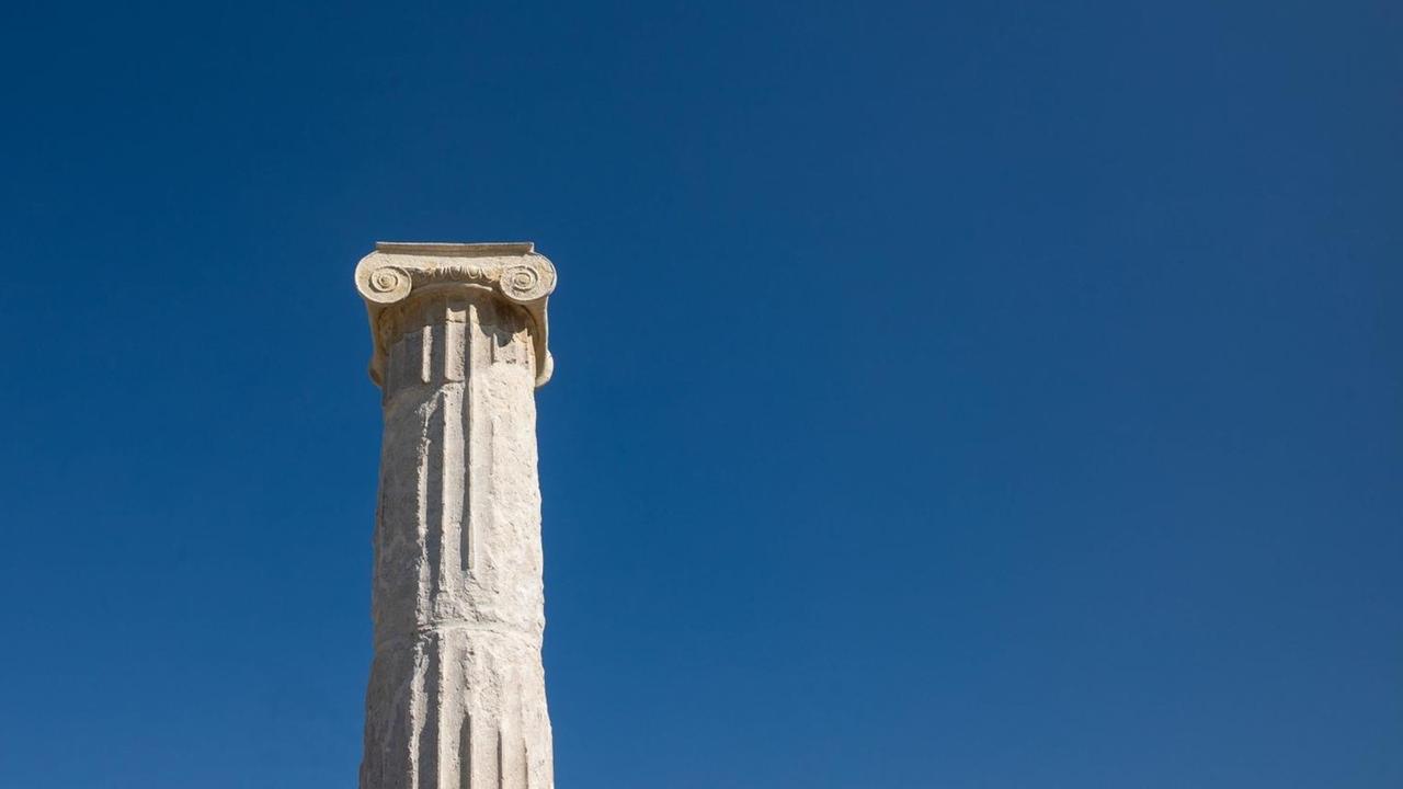Weiße Säule mit Kapitell in Pella, der antiken Hauptstadt Mazedoniens in Griechenland vor blauem Himmel.