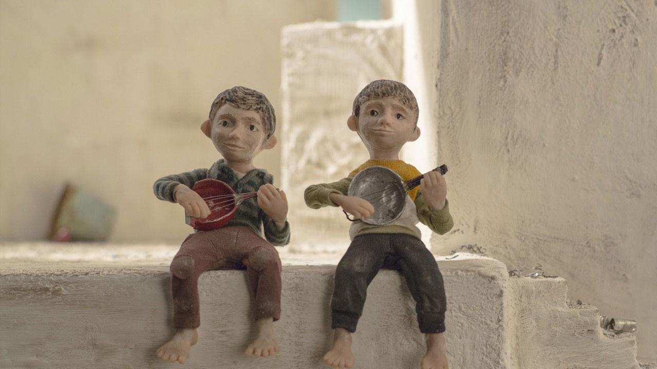 Zwei Jungen sitzen nebeneinander auf einer Mauer und spielen Laute