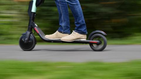Die Füße eines Mannes auf einem E-Scooter.