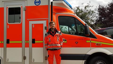 Leon steht vor einem Rettungswagen