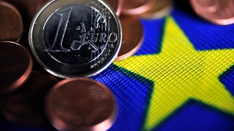 Euro-Münzen liegen auf einer EU-Flagge