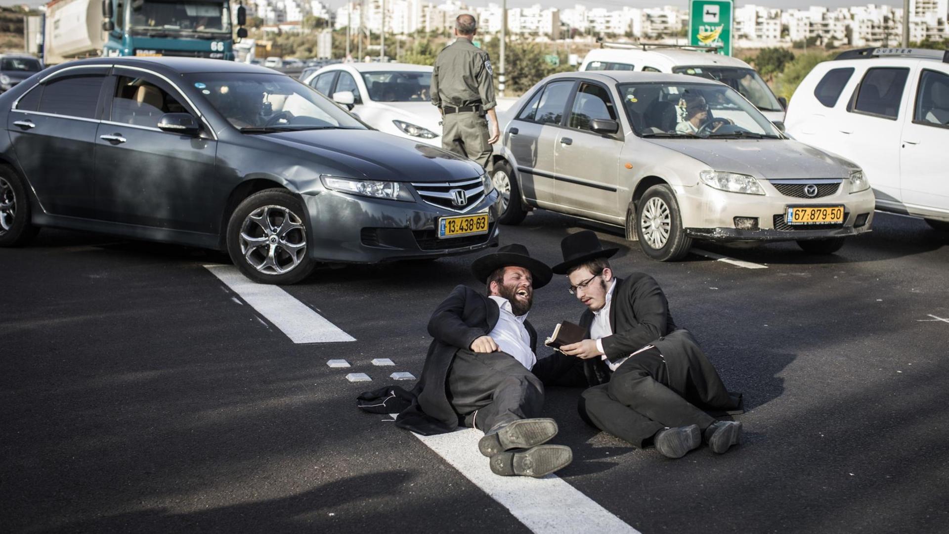 Ultraorthodoxe jüdische Männer blockieren während einer Demonstration für die Befreiung vom Wehrdienst eine Straße
