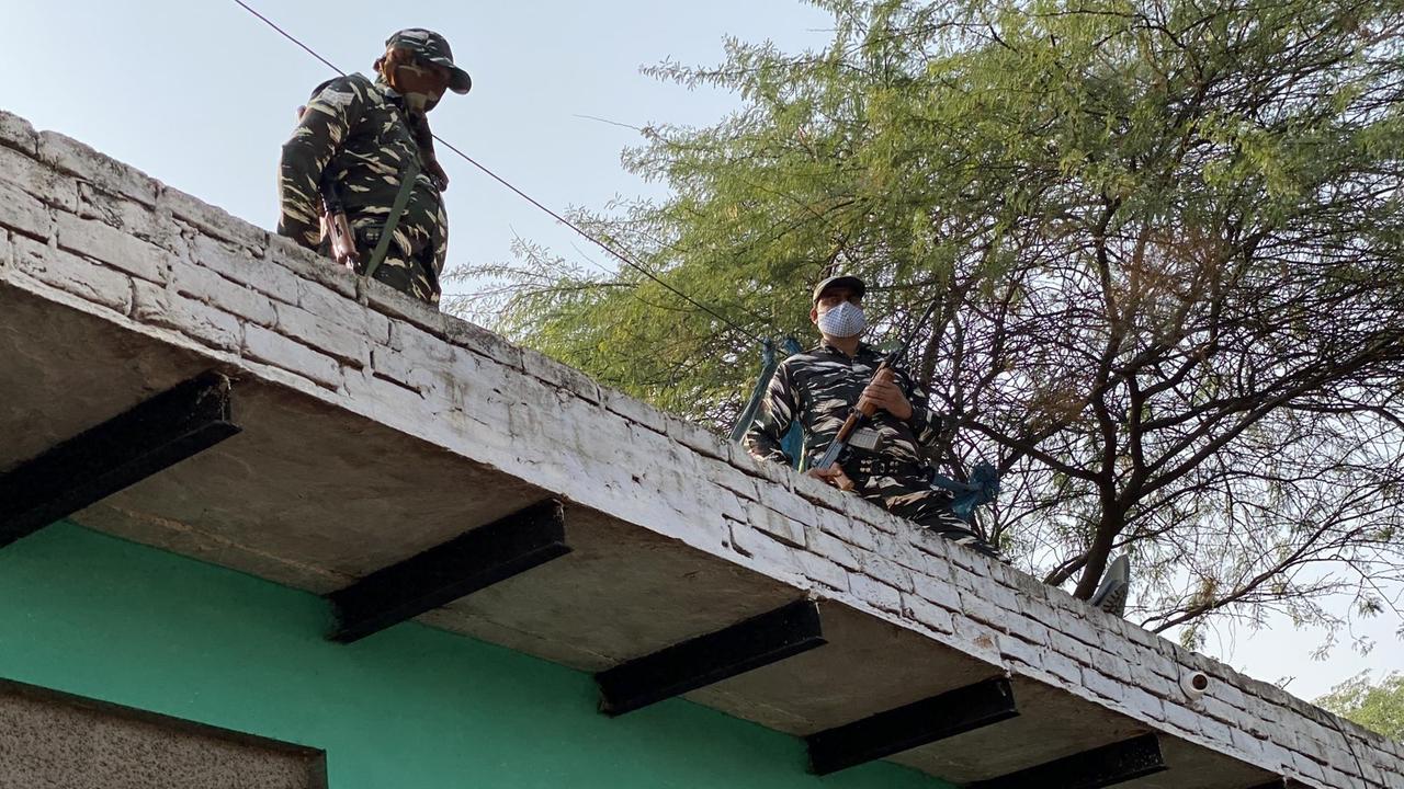 Zwei bewaffnete Militärs patroullieren bewaffnet auf dem Dach eines Hauses.