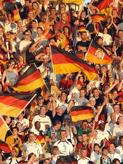 Fans schwenken 2006 im Stadion in Stuttgart deutsche Fahnen