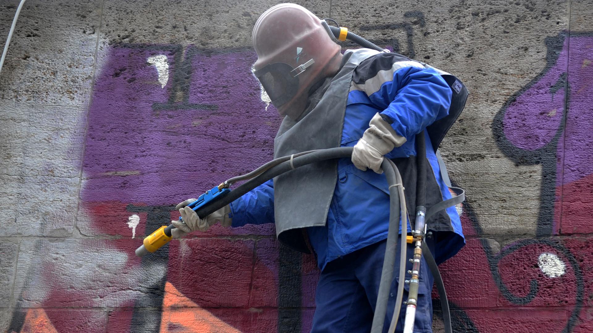 Ein Arbeiter des Baureferats mit Schutzhelm entfernt von der Ludwigsbrücke in München ein Graffiti. Metallschlacke, mit Hochdruck aufgesprüht, reinigt den Sandstein. Ein Arbeiter des Baureferats mit Schutzhelm entfernt von der Ludwigsbrücke in München ein Graffiti. Metallschlacke, mit Hochdruck aufgesprüht, reinigt den Sandstein.