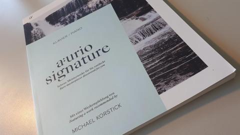 Auf einer Tischplatte liegt ein helles Magazin, auf dem "aurio signature" steht.