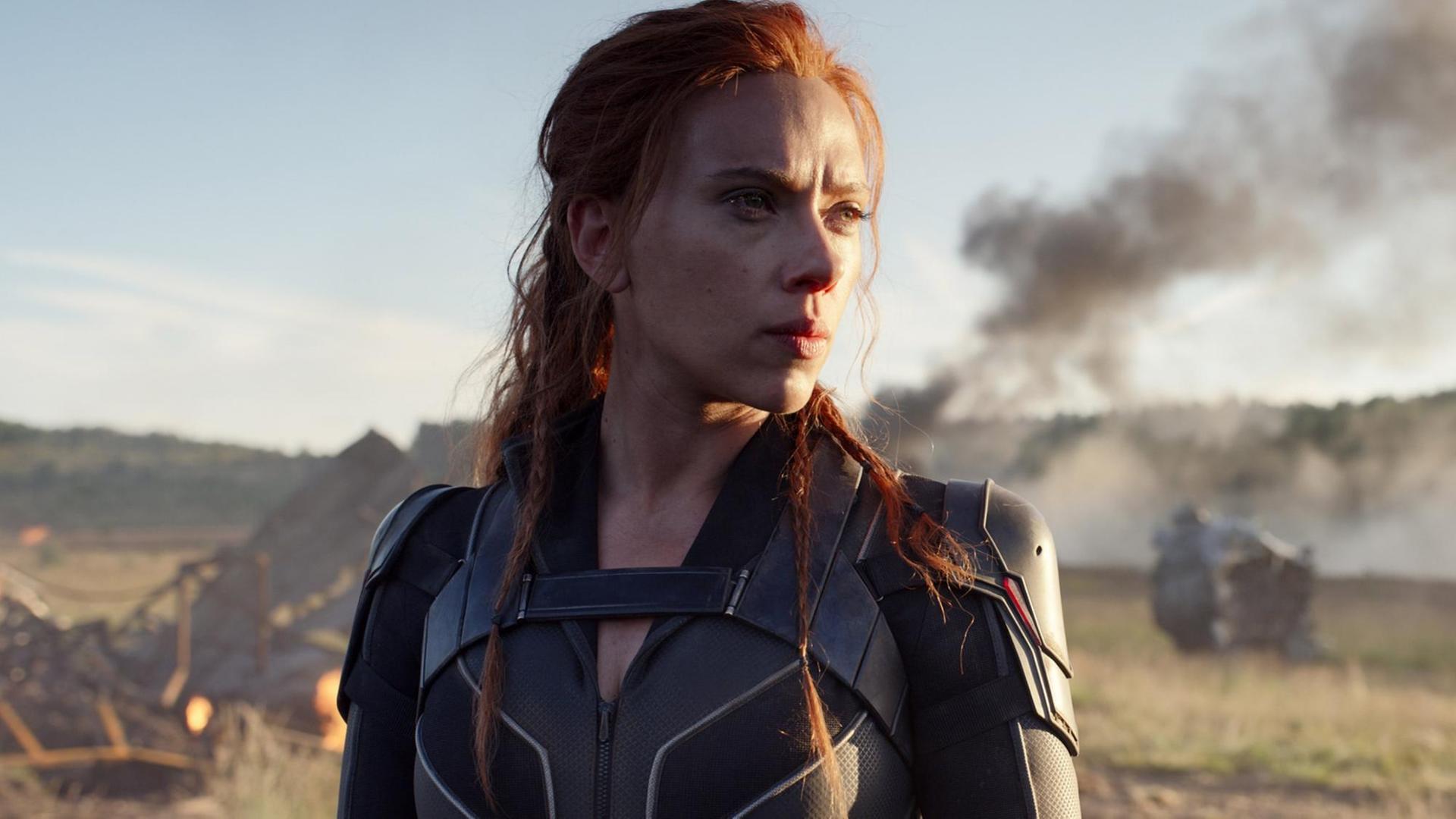 Die Schauspielerin Scarlett steht in einer Filmszene von "Black Widow"auf einem Feld mit Rauch im Hintergrund Die Schauspielerin Scarlett steht in einer Filmszene von "Black Widow"auf einem Feld mit Rauch im Hintergrund