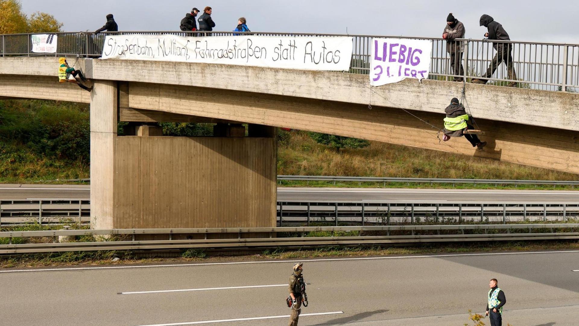 Hessen, Idstein: Umweltaktivisten hängen an einer Brücke über der Autobahn 3 und protestieren gegen die Rodung von Bäumen im Herrenwald und Dannenröder Forst bei Stadtallendorf im Zusammenhang mit dem geplanten Ausbau der Autobahn 49.