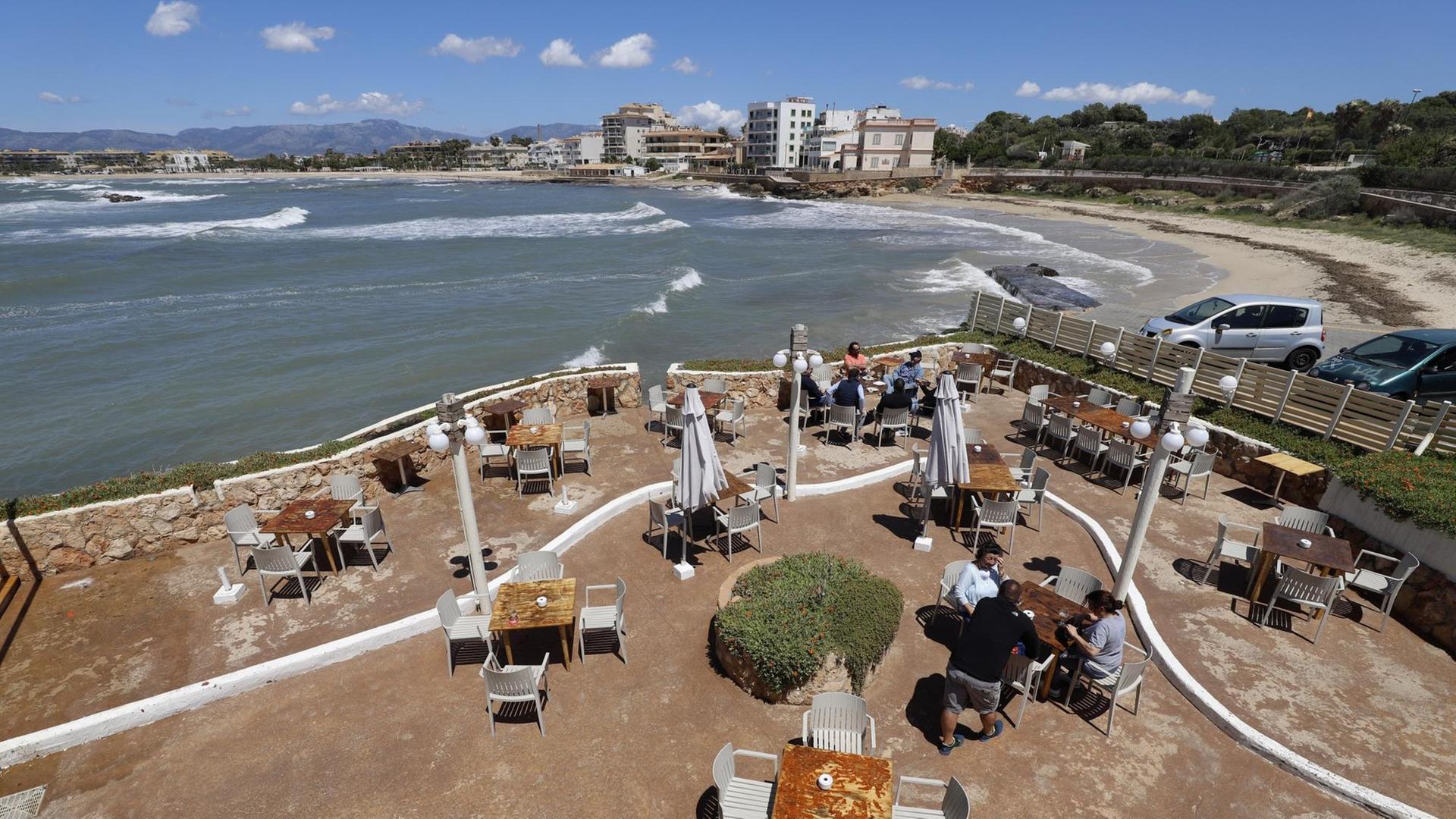 Menschen sitzen auf der Terrasse der Bar El Pe-on am Meer, Spanien.