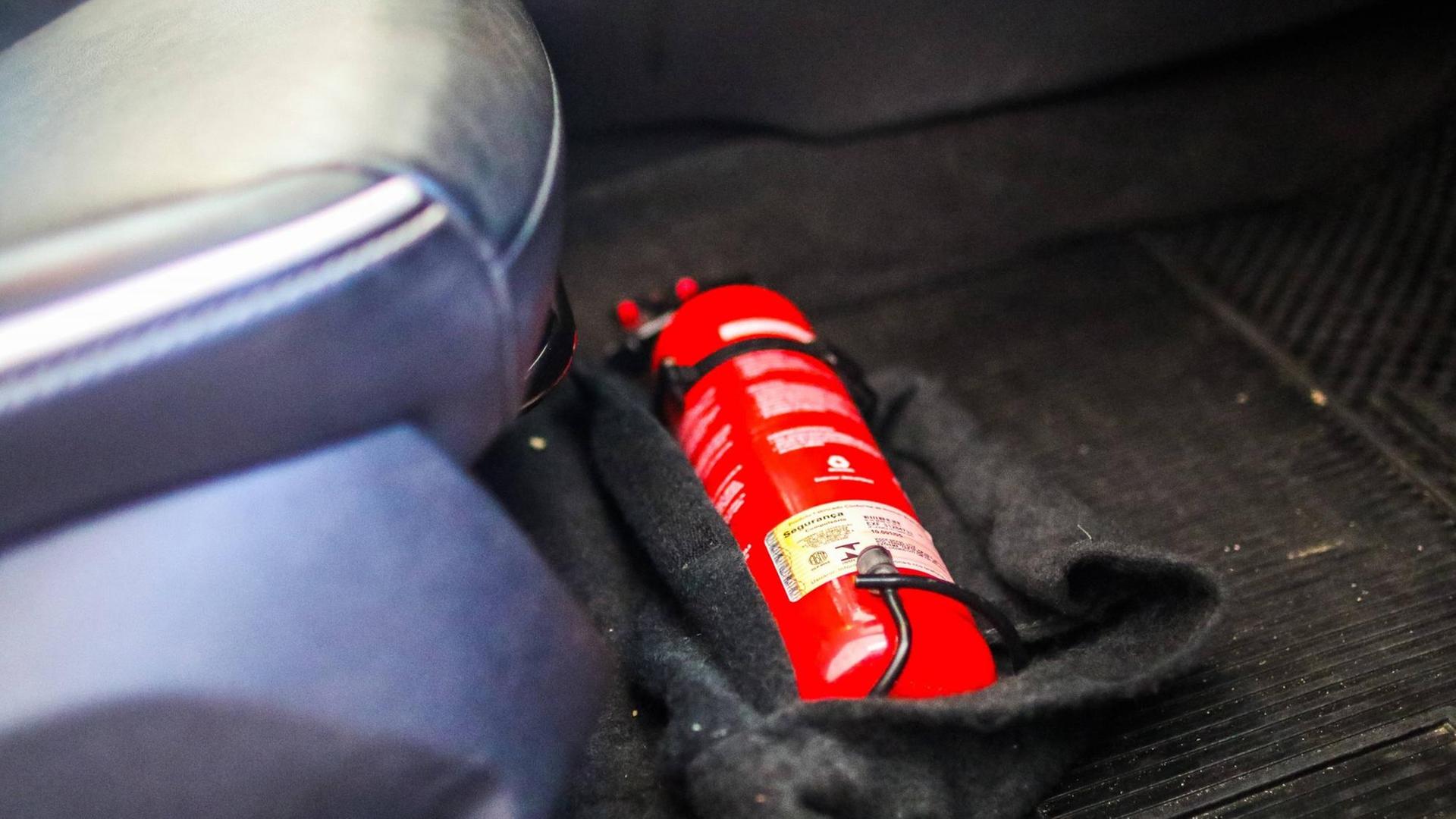 Ein Feuerlöscher liegt fest verschraubt unter dem Fahrersitz in einem Auto.