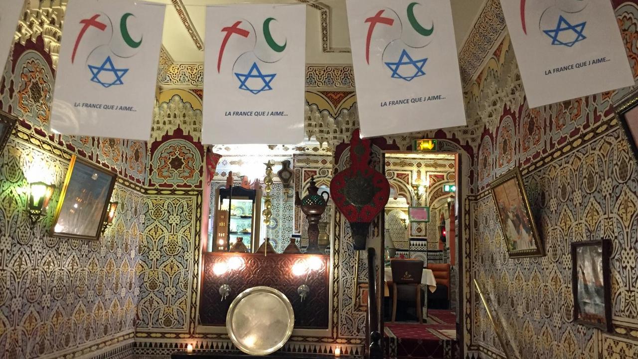 Fähnchen mit  christlichen, muslimischen und jüdischen Symbolen hängen in einem Restaurant 