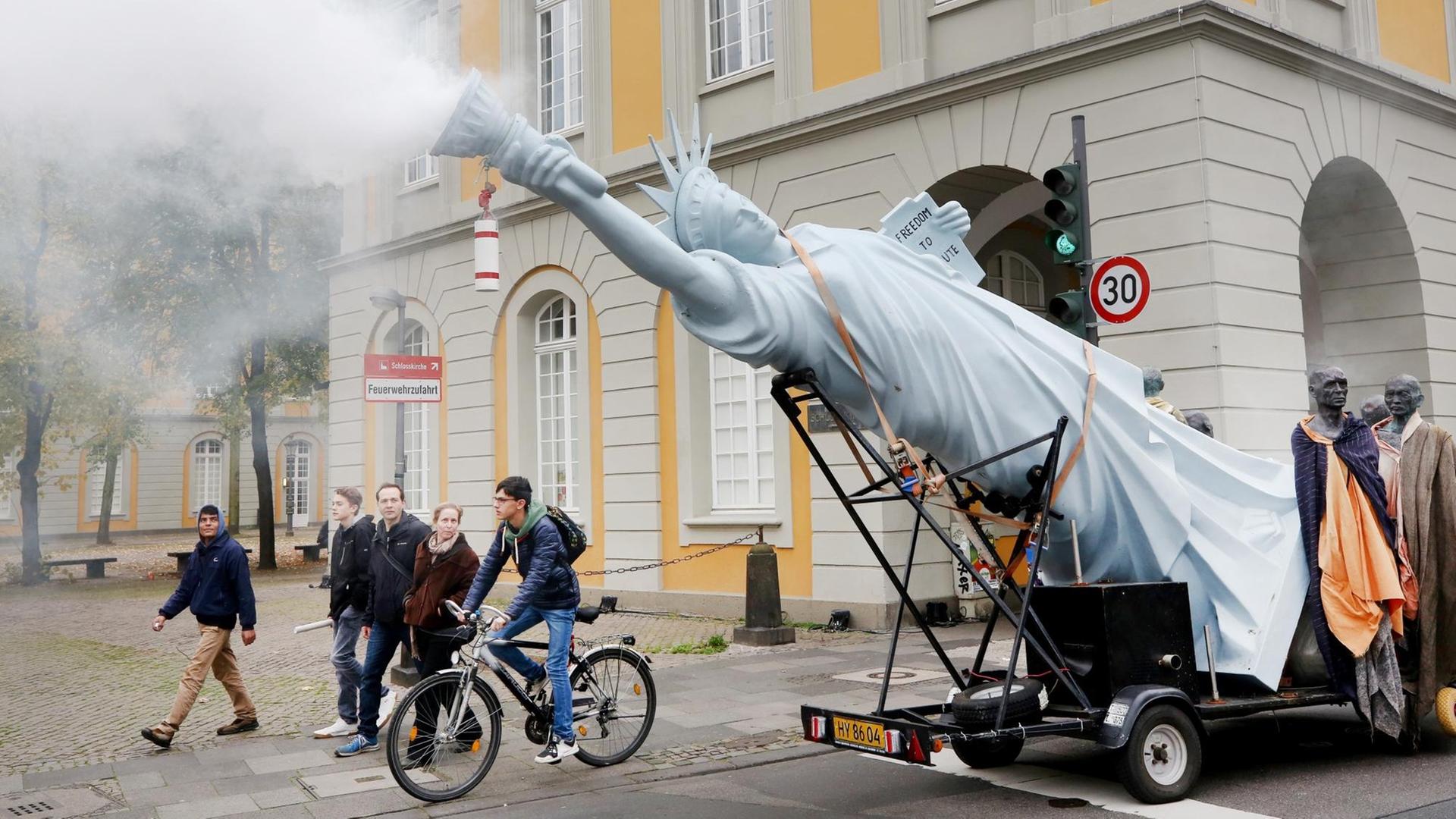 Mit einer qualmenden Freiheitsstatue ziehen Demonstranten am 04.11.2017 in Bonn (Nordrhein-Westfalen) für die Umsetzung des Weltklimaabkommens durch die Innenstadt. Die Demonstration findet im Vorfeld der Weltklimakonferenz statt, die am 06.11.2017 in Bonn beginnt
