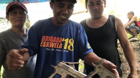 Joel und Nilo zeigen stolz die in ihrer illegalen Urwaldwerkstatt gefertigen Pistolen.