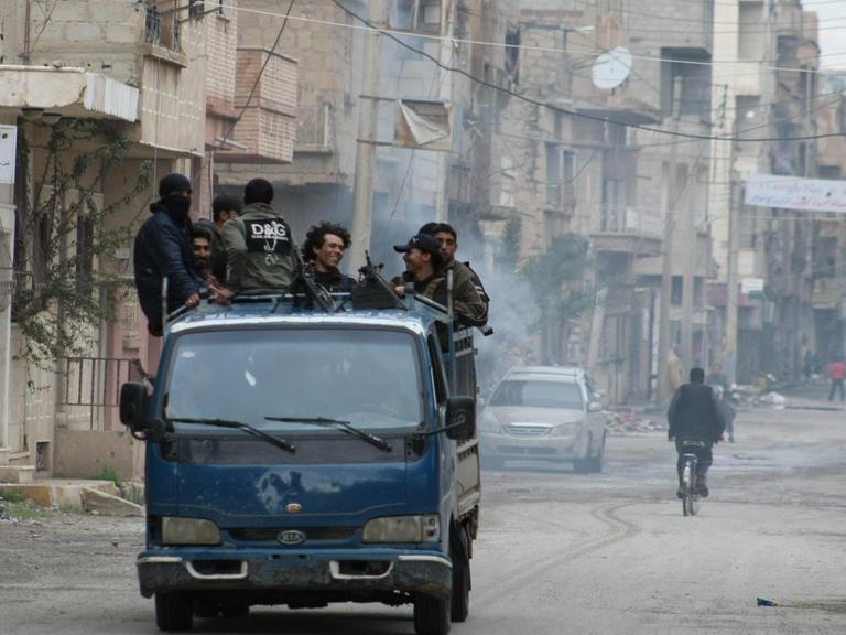 Rebellen stehen auf der Ladefläche eines Pick-ups und fahren am 10.03.2014 durch die ost-syrische Stadt Deir al-Sor. PHOTO / AHMAD ABOUD