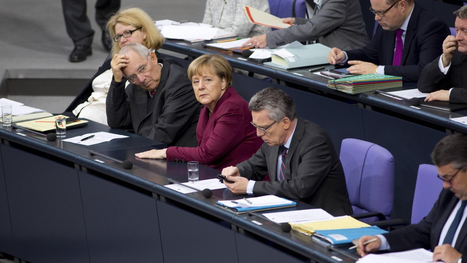 Bundesfinanzminister Wolfgang Schäuble, Bundeskanzlerin Angela Merkel und Bundesinnenminister Thomas de Maizière auf der Regierungsbank im Bundestag.