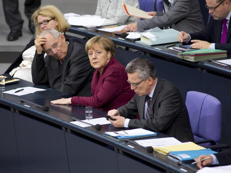 Bundesfinanzminister Wolfgang Schäuble, Bundeskanzlerin Angela Merkel und Bundesinnenminister Thomas de Maizière auf der Regierungsbank im Bundestag.