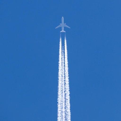 Flugzeug mit Kondensstreifen vor blauem Himmel