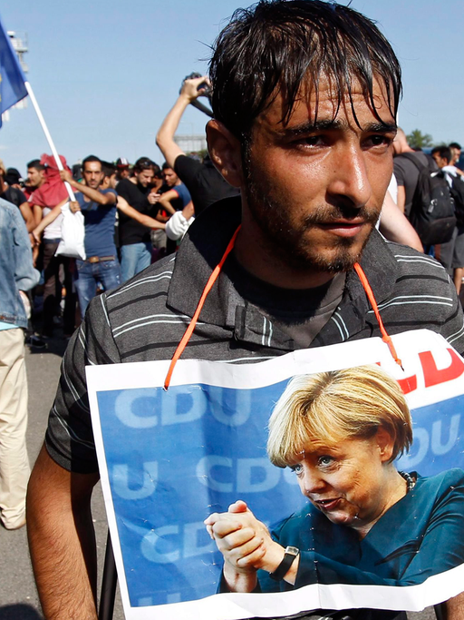Ein Flüchtling in Ungarn mit einem Foto von Angela Merkel