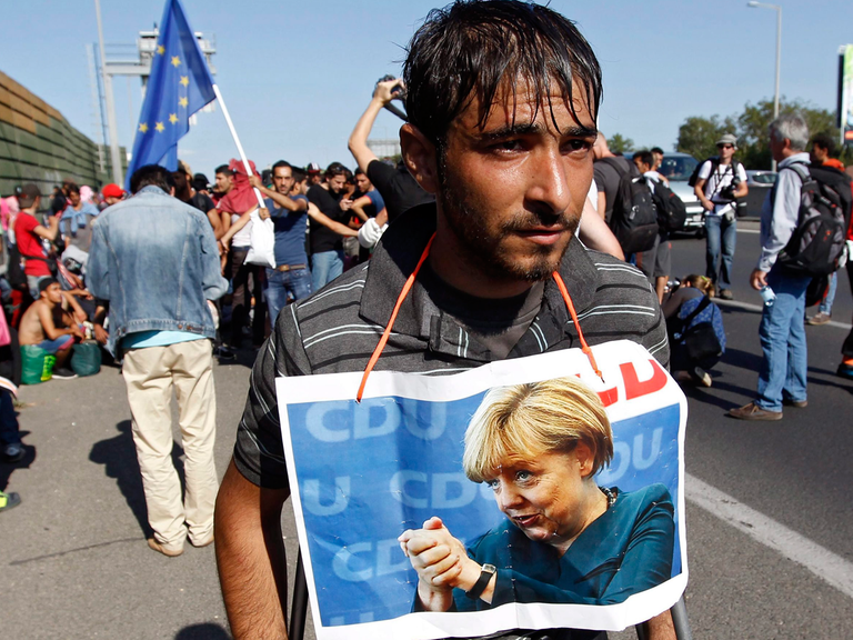 Ein Flüchtling in Ungarn mit einem Foto von Angela Merkel