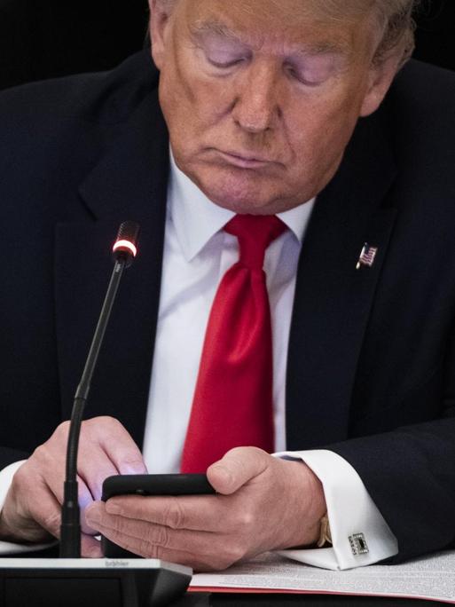 US-Präsident Donald Trump schaut auf sein Smartphone.