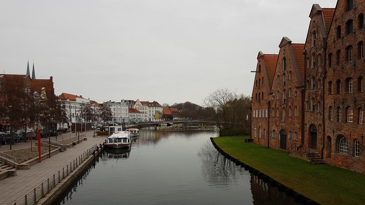 Ein Backstein-Gebäude ist rechts eines Kanals zu sehen, links davon moderne Häuser