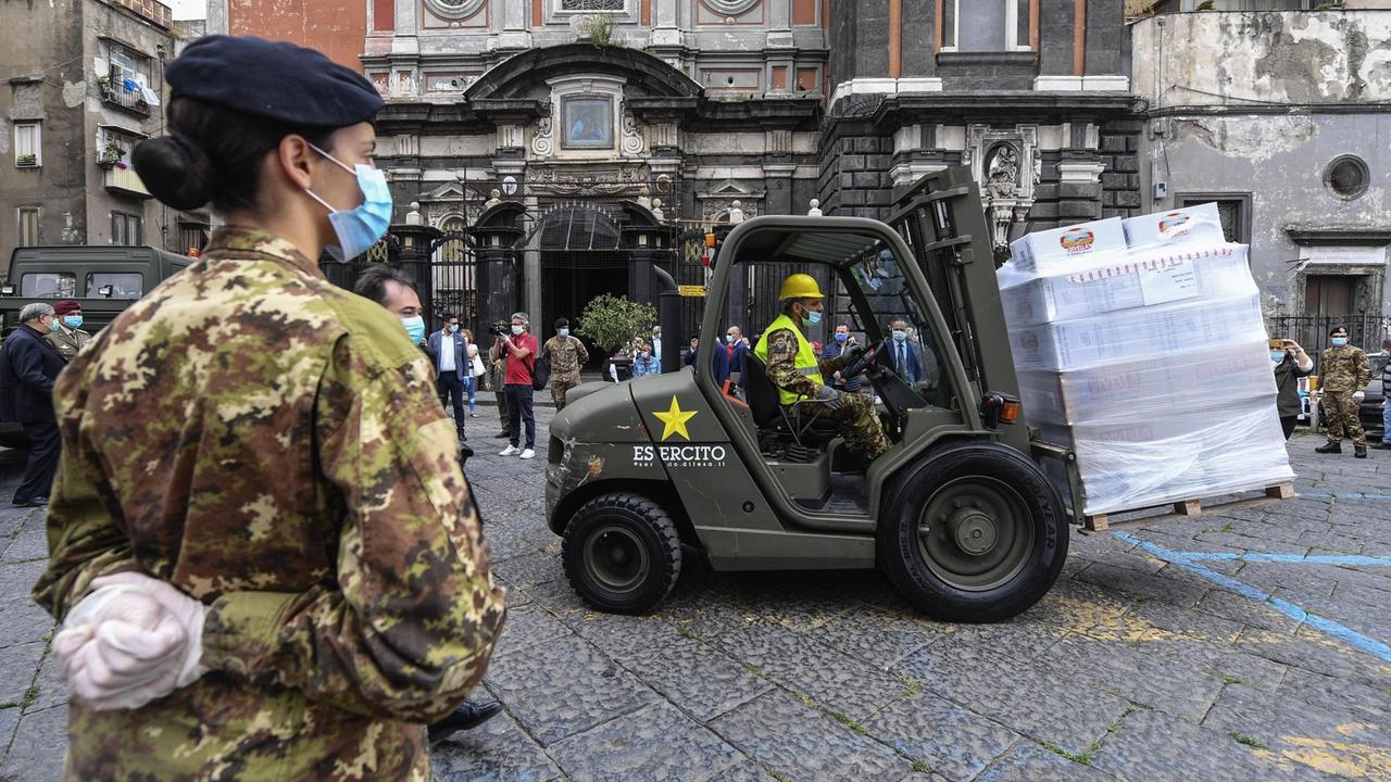 Soldaten mit Schutzmasken transportieren mit einem Gabelstapler Essen vor einer Kirche in Neapel