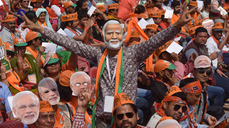 Inder tragen auf einer Demonstration Masken mit dem Bild von Indiens Premierminister Narendra Modi.