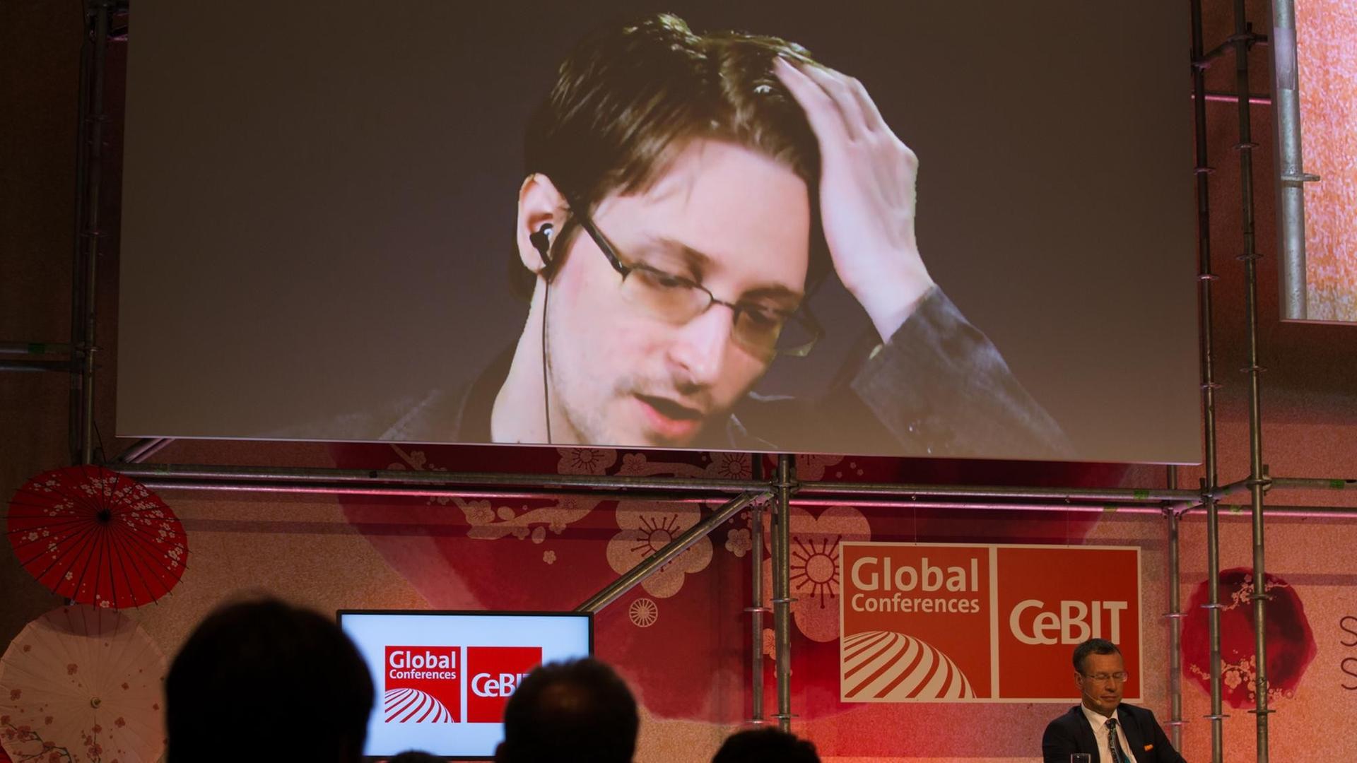 Der US-amerikanische Whistleblower und ehemalige CIA-Mitarbeiter Edward Snowden spricht am 21.03.2017 bei der IT-Messe CeBIT in Hannover (Niedersachsen) auf einer Videowand. Die IT-Messe CeBIT will ihr Fachpublikum mit konkreten Anwendungsbeispielen für neue Technologien überzeugen. Zu der fünftägigen Veranstaltung (20.-24. März) mit über 3000 Ausstellern aus 70 Ländern werden rund 200000 Besucher erwartet. Partnerland ist Japan.
