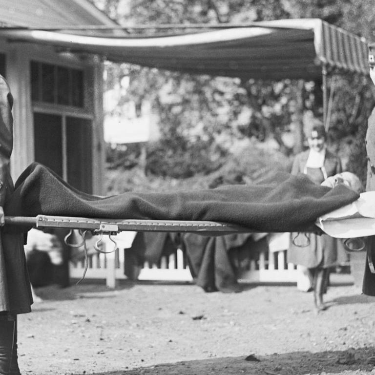 Zwei Krankenpflegerinnen tragen einen Patienten während der Pandemie, der spanischen Grippe, in Washington DC, USA, 1918.