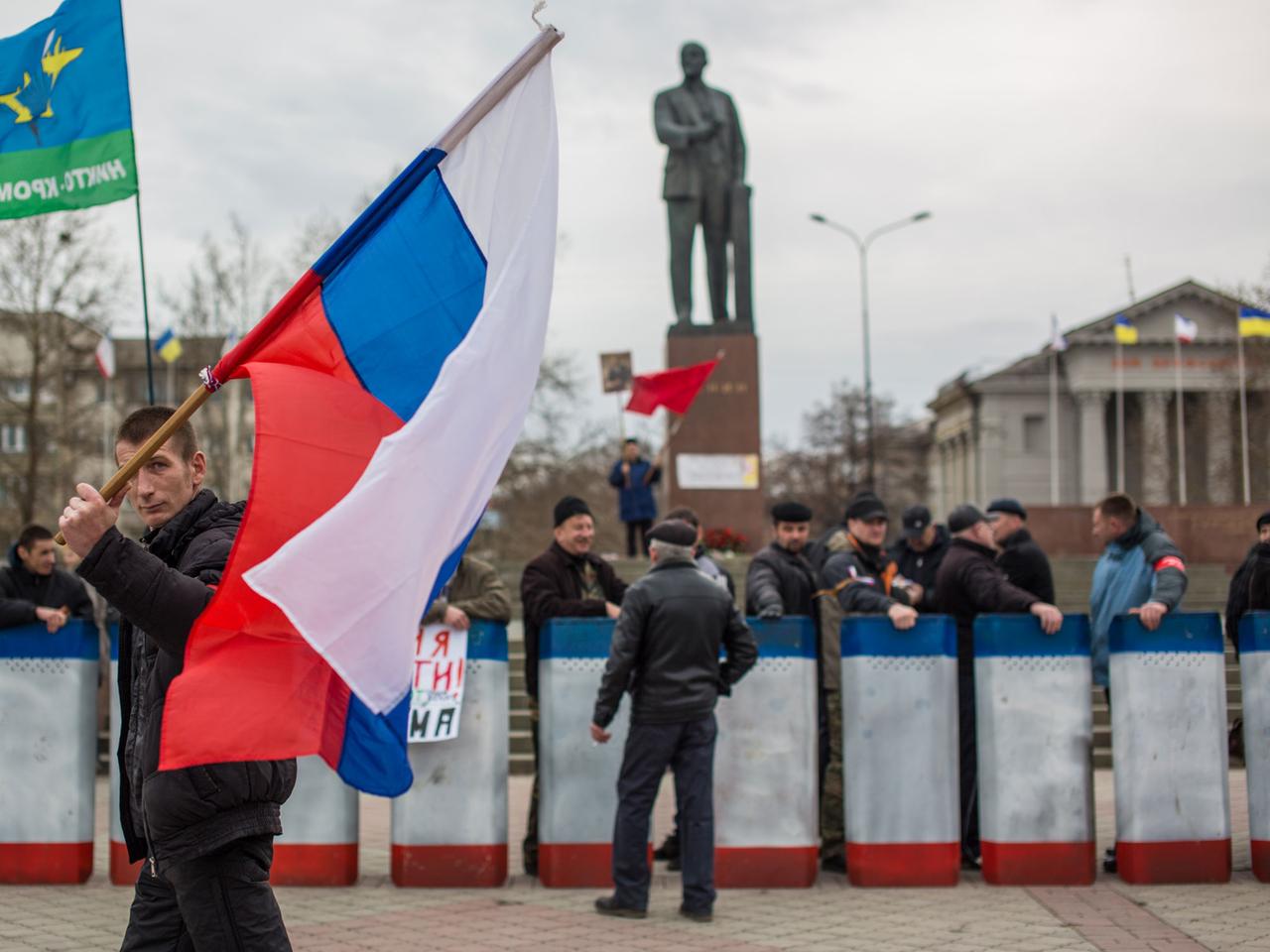 Ein Demonstrant trägt eine russische Flagge.