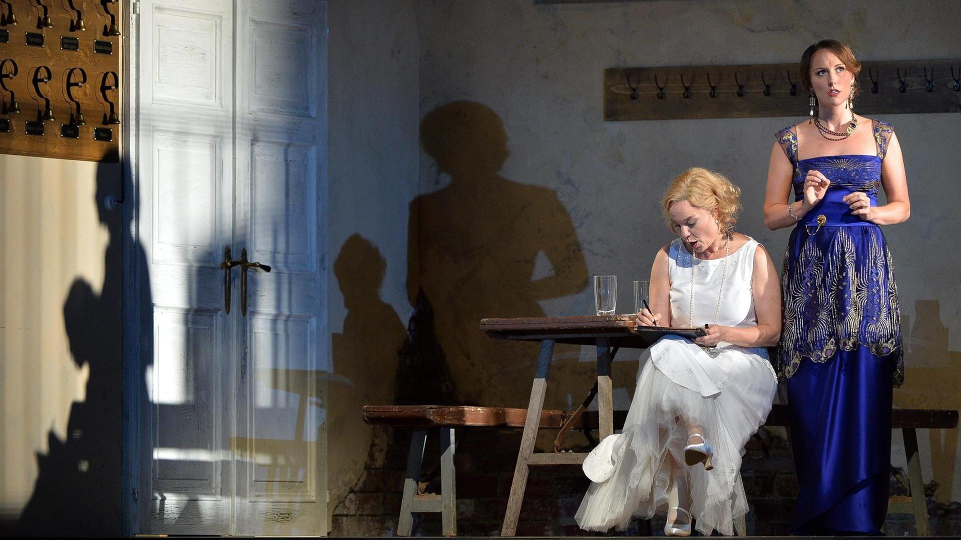 Szene aus "Le Nozze di Figaro" auf der Bühne, eine Frau sitzend, eine Frau stehend in Abendkleidern.