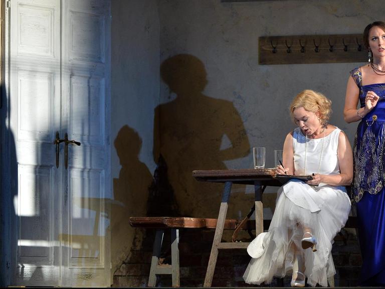 Szene aus "Le Nozze di Figaro" auf der Bühne, eine Frau sitzend, eine Frau stehend in Abendkleidern.