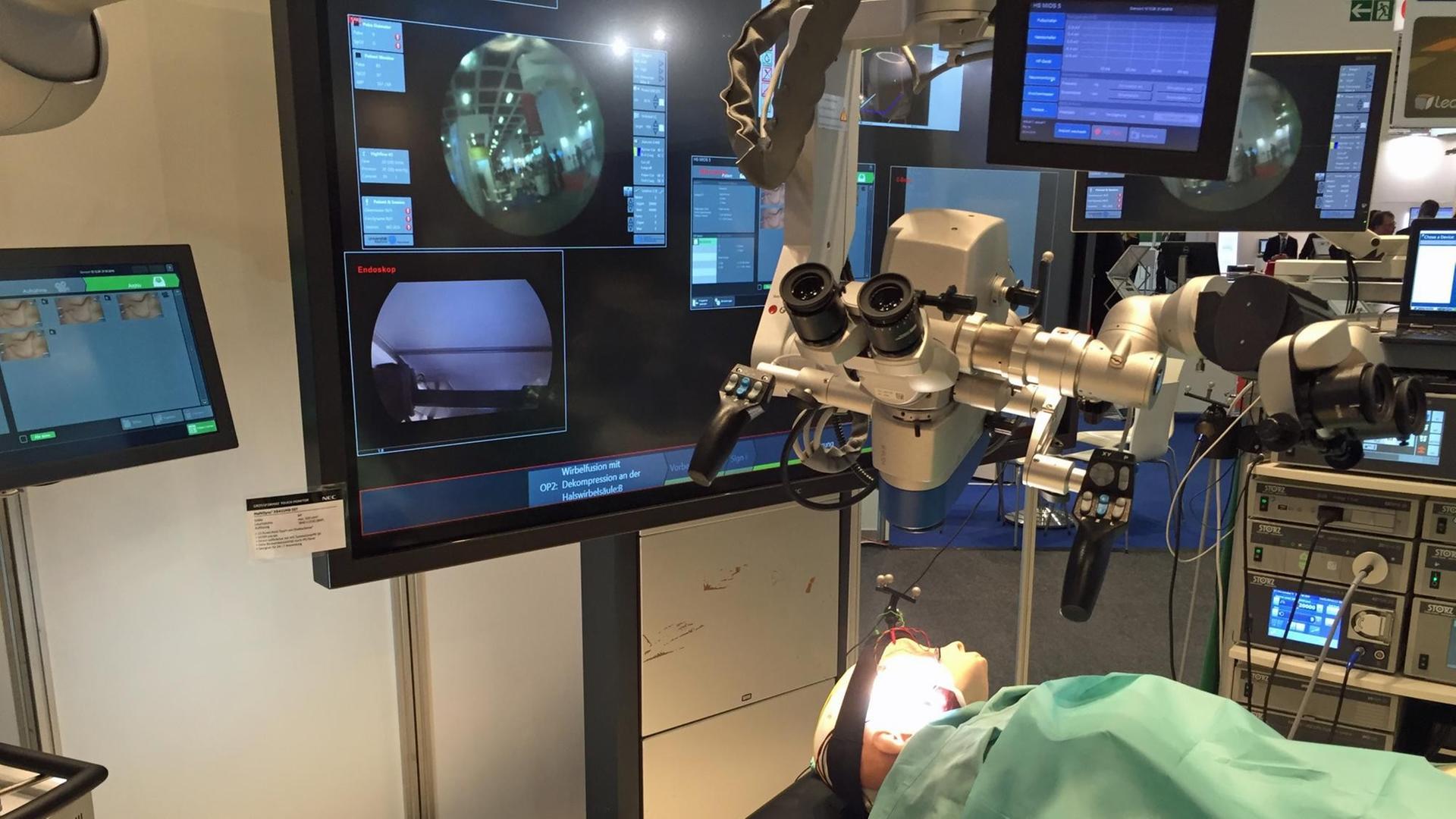 Ein Operationssaal mit diversen Bildschirmen und Mikroskopen, darunter liegt auf einem OP-Tisch ein Dummy.