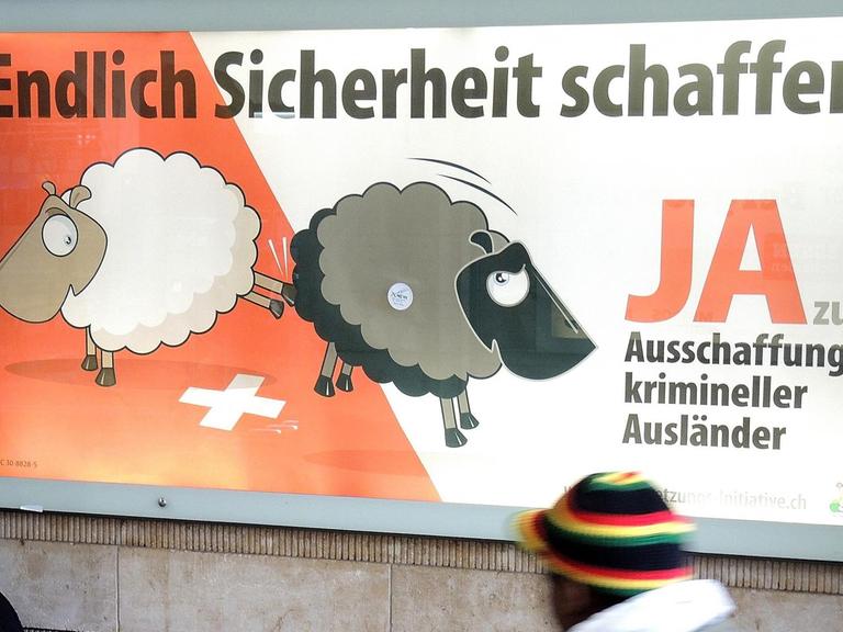 Ein Mann geht am Hauptbahnhof von Basel an einem Plakat der Schweizerischen Volkspartei (SVP) vorbei, auf dem die Ausweisung (Ausschaffung) krimineller Ausländer gefordert wird.