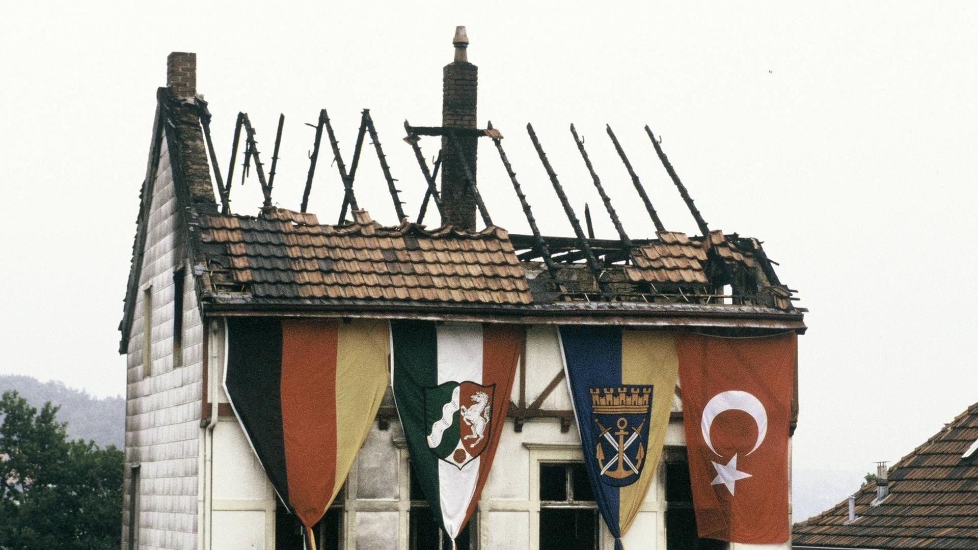 Ein durch ein Feuer stark beschädigtes Haus in Solingen. An der äußeren Fassade hängen mehrere Flaggen, darunter die türkische.