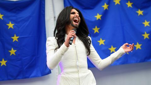 Conchita Wurst singt im Europaparlament in Brüssel vor zwei EU-Flaggen.