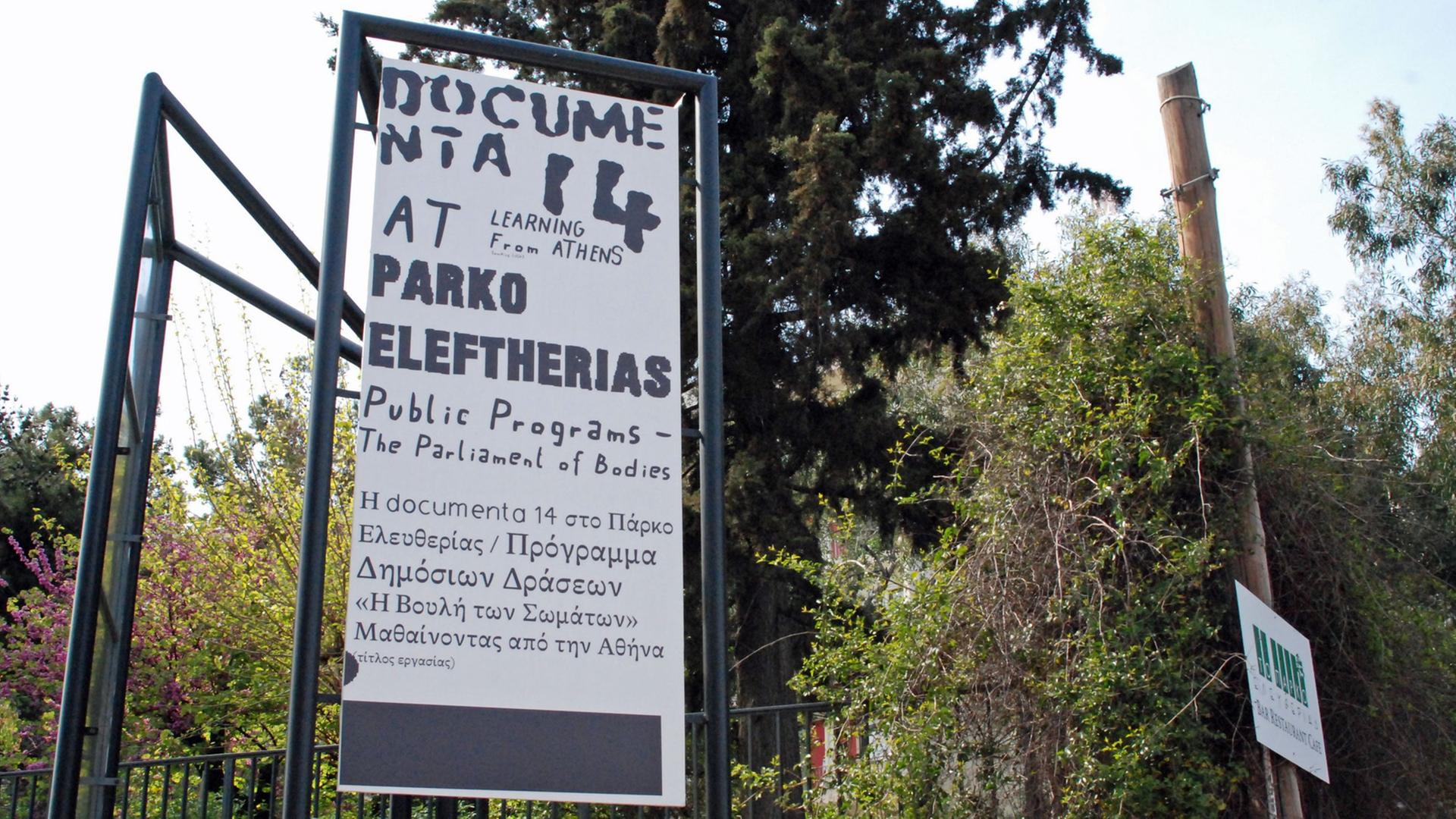 Ein Werbe-Plakat für die documenta hängt am Zaun von einem Park in Athen.