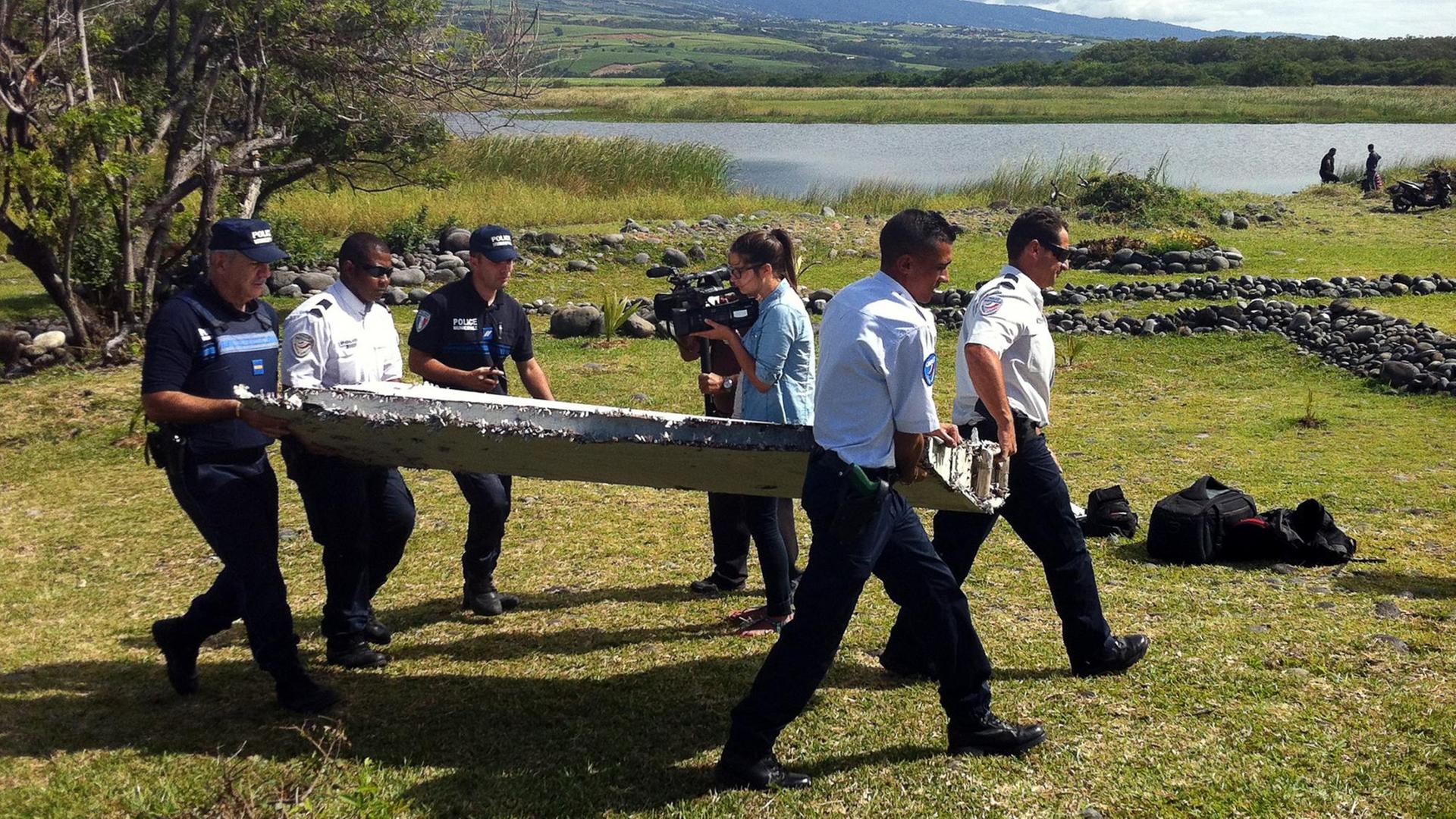 Nach mehr als einem Jahr eine erste Spur von Flug MH370? Polizisten mit dem auf der Insel La Réunion gefundenen Wrackteil.