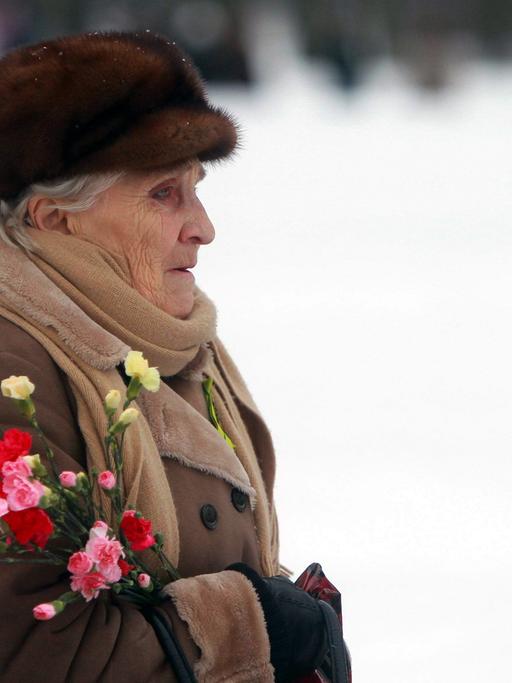 Eine alte Frau mit Blumen im Arm auf einer Gedenkveranstaltung in St. Petersburg zur Erinnerung an das Ende der Leningrader Blockade durch die Nazis, die von 1941-1944 dauerte.